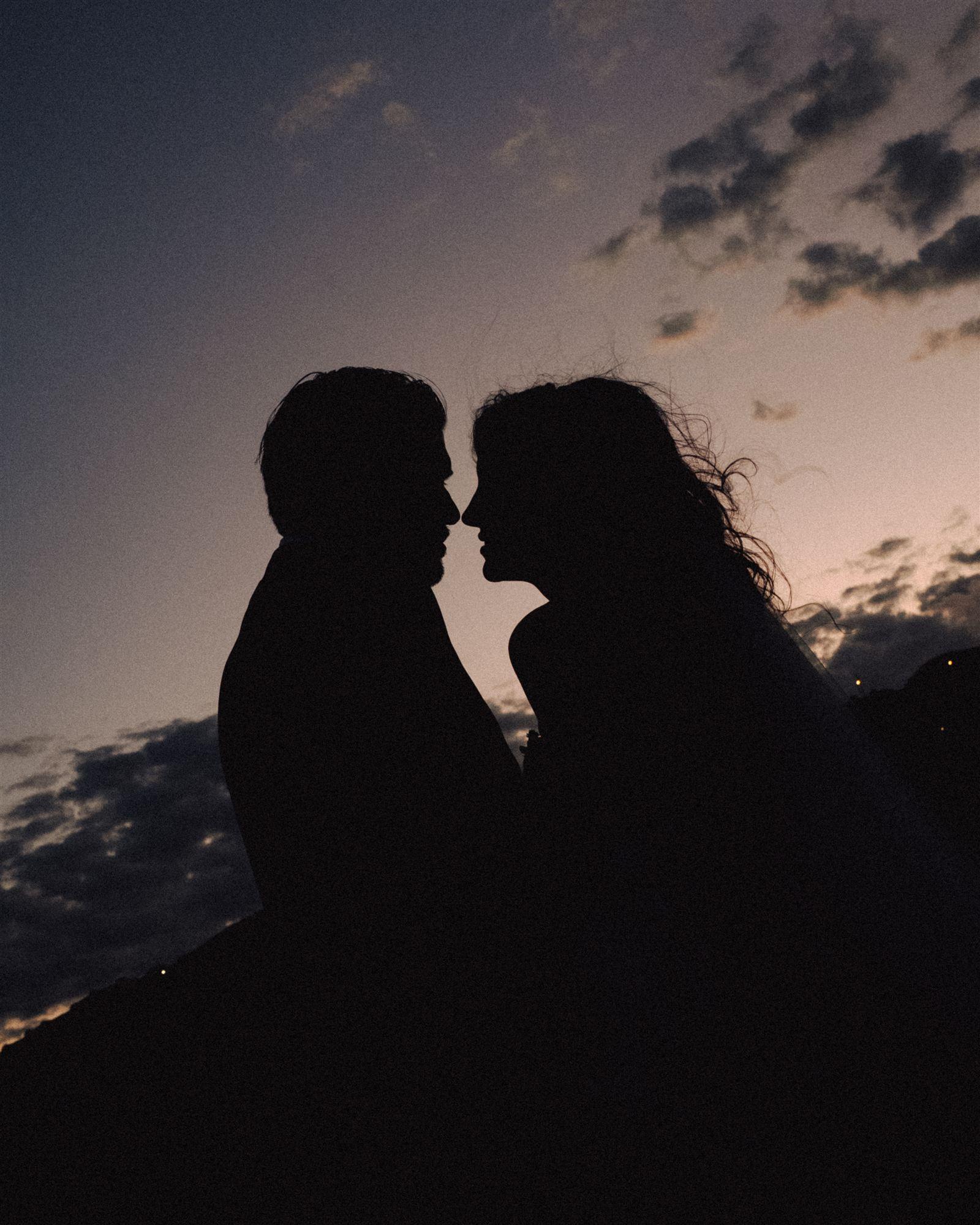 Silhouette of a couple kissing at dusk against a fading sky