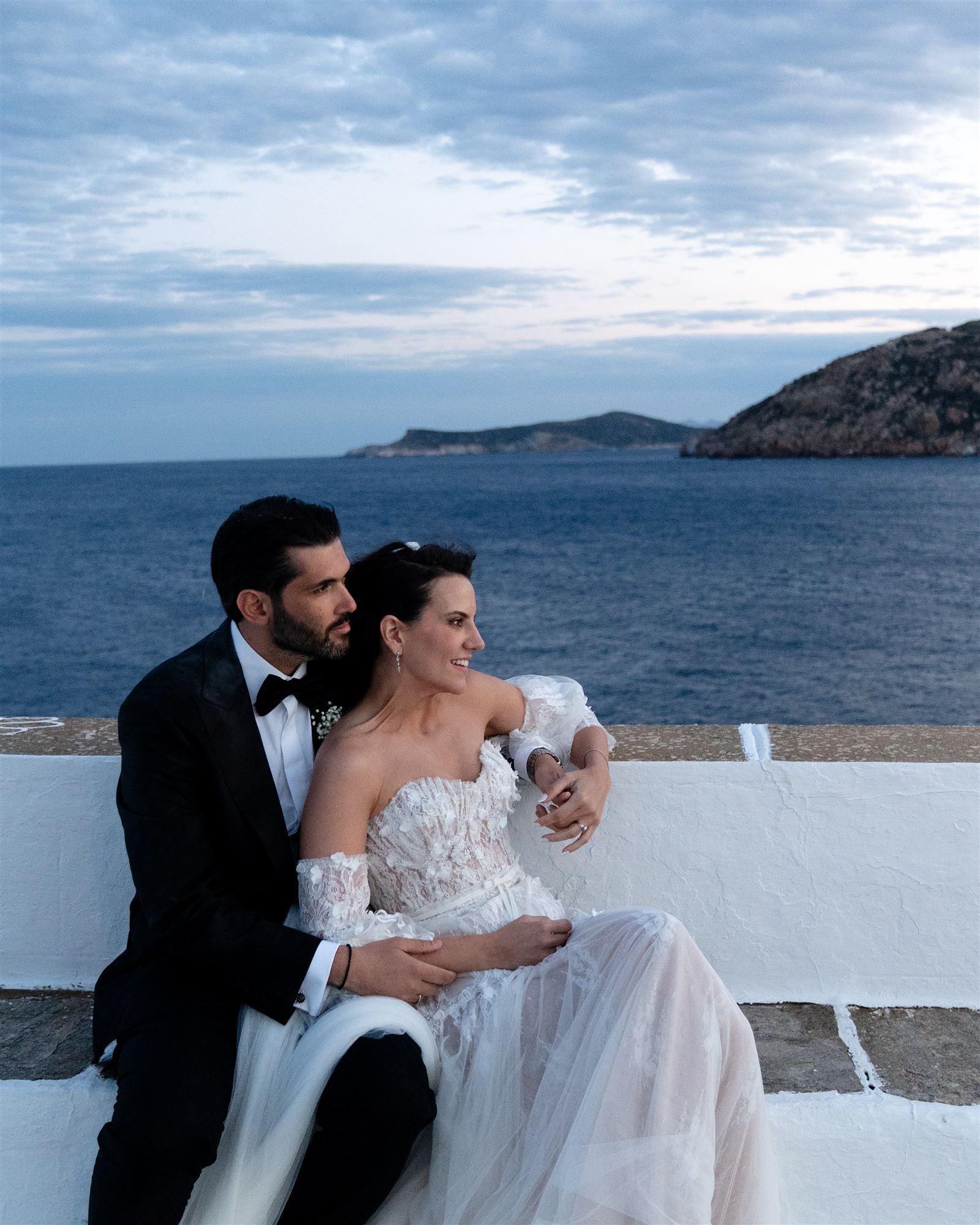 Couple embracing close together with the sea and hills behind them at sunset