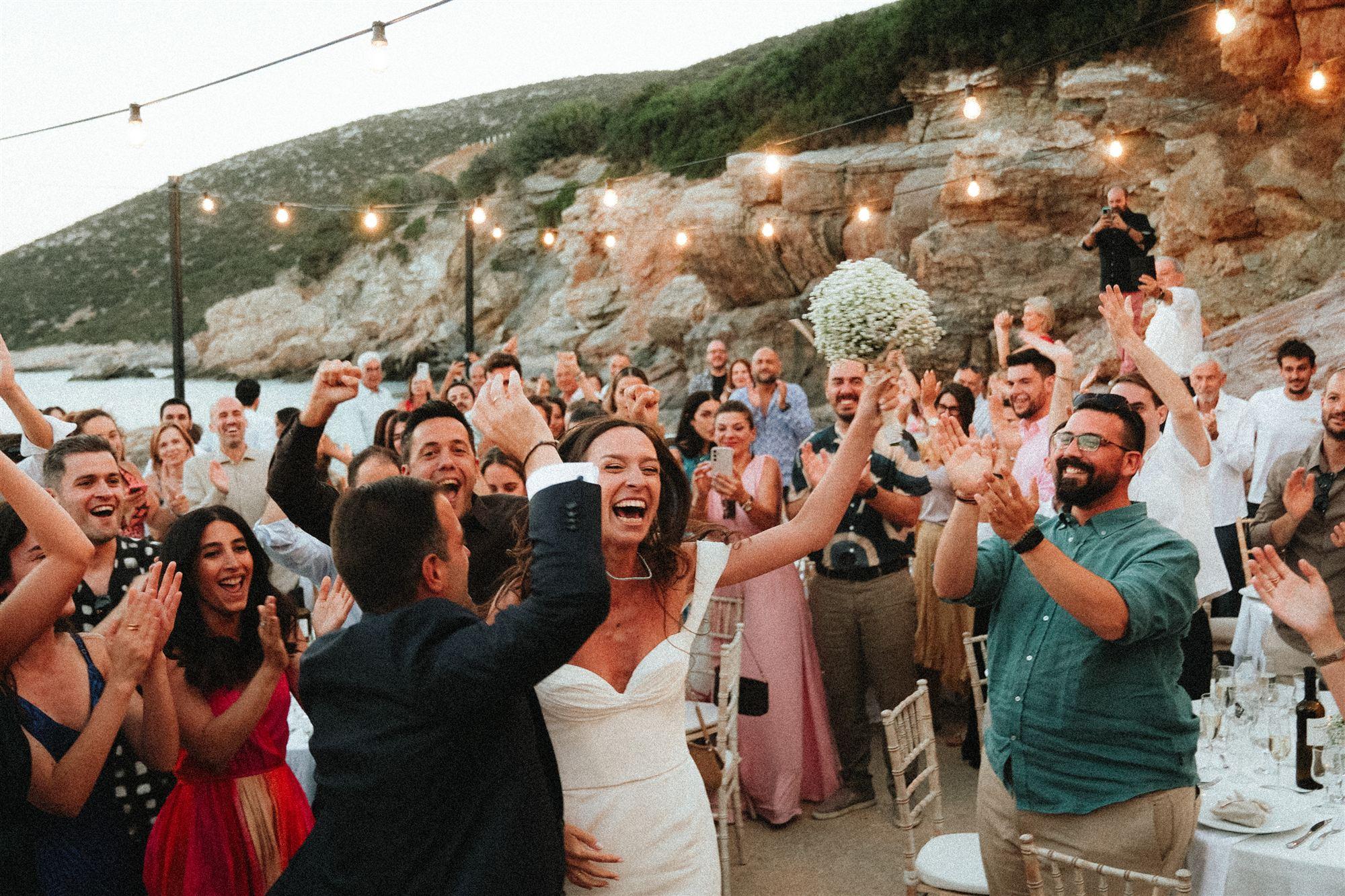Wedding guests cheering under string lights during the reception