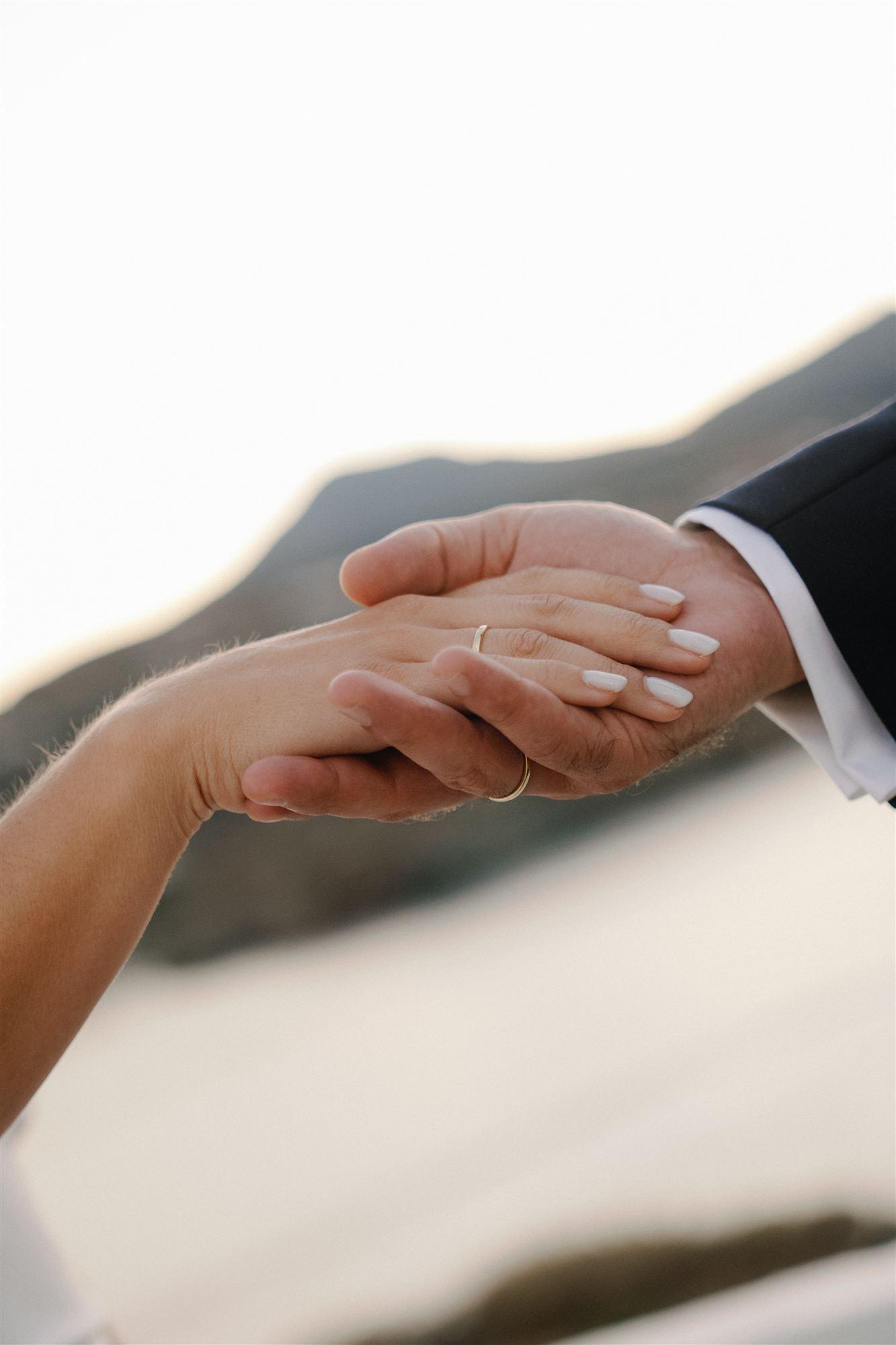 Close detail of the couple's hands and wedding rings