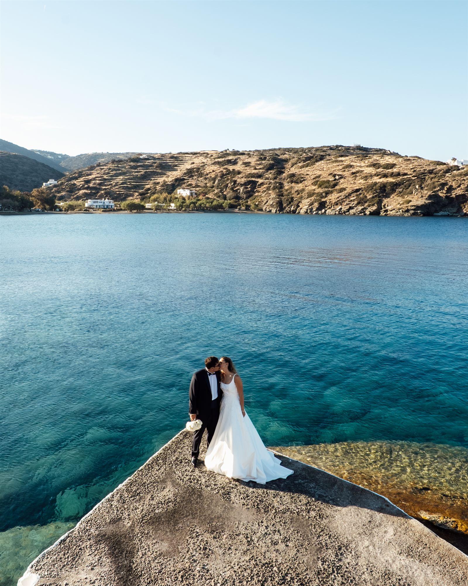 Aerial view of a couple embracing on a rocky point over turquoise water